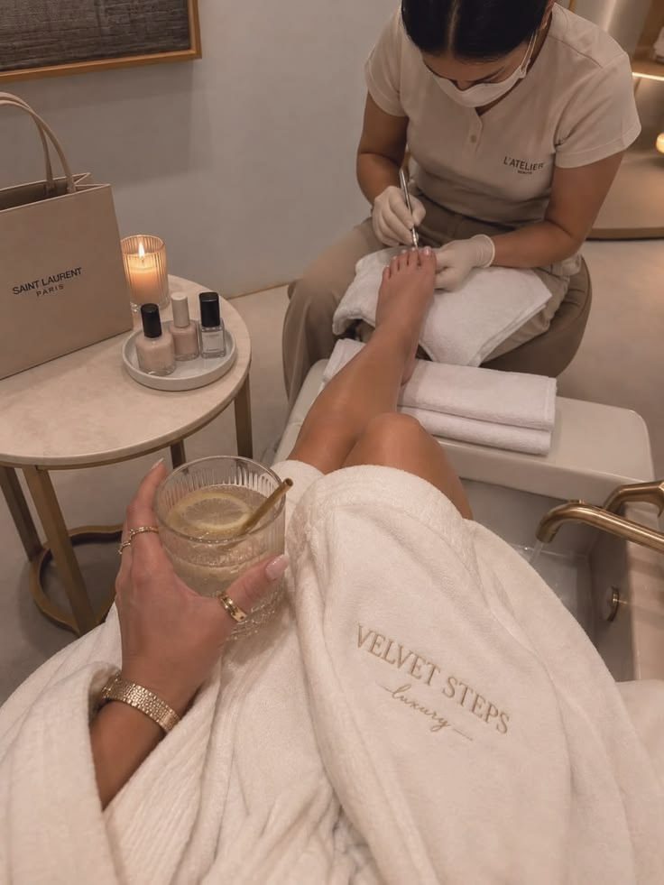 A luxury pedicure in a robe, with a drink